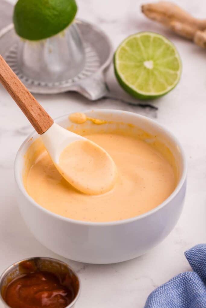 Bowl of mayo with a spatula lifting the mayo out of the bowl.