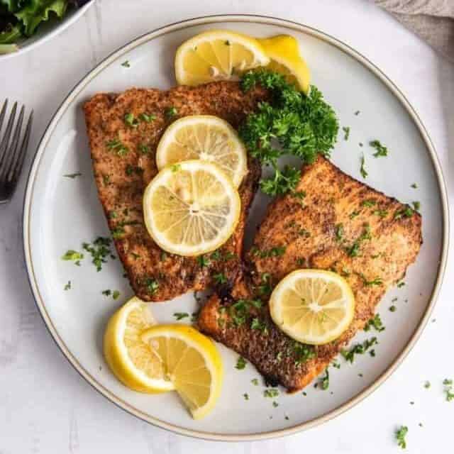 plate with two air fryer salmon fillets with lemon slices