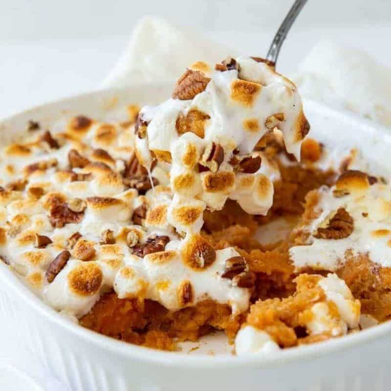 Sweet Potato Casserole with a hand pulling a serving spoon piece out