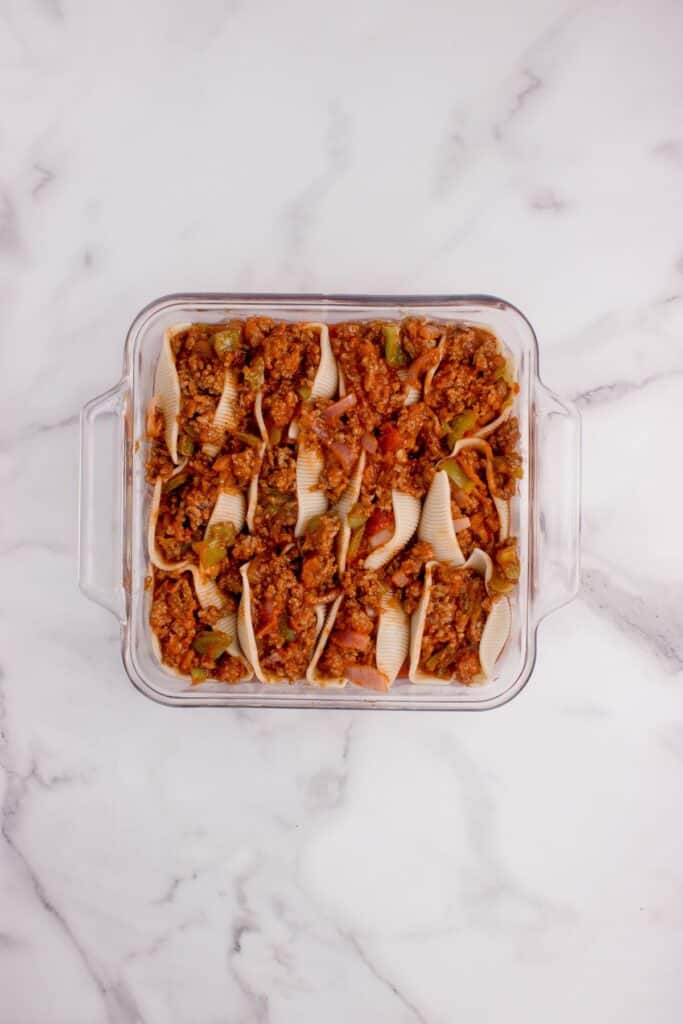 Prepped and filled shells are lined in a casserole dish.