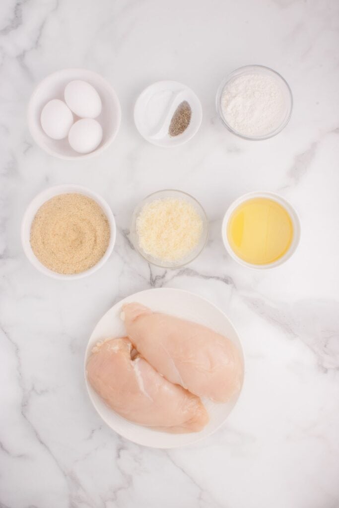 Ingredients for breaded chicken cutlets: eggs, salt, pepper, flour, seasoned breadcrumbs, parmesan cheese, and oil.