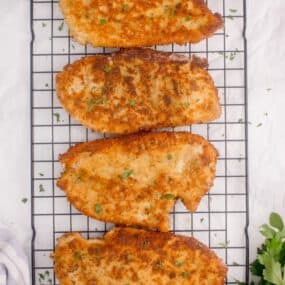 Baking rack with four pan fried chicken cutlets.