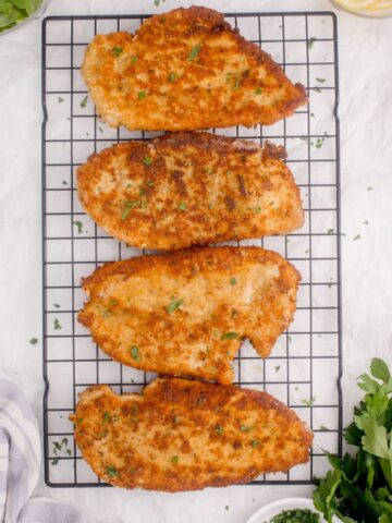 Baking rack with four pan fried chicken cutlets.