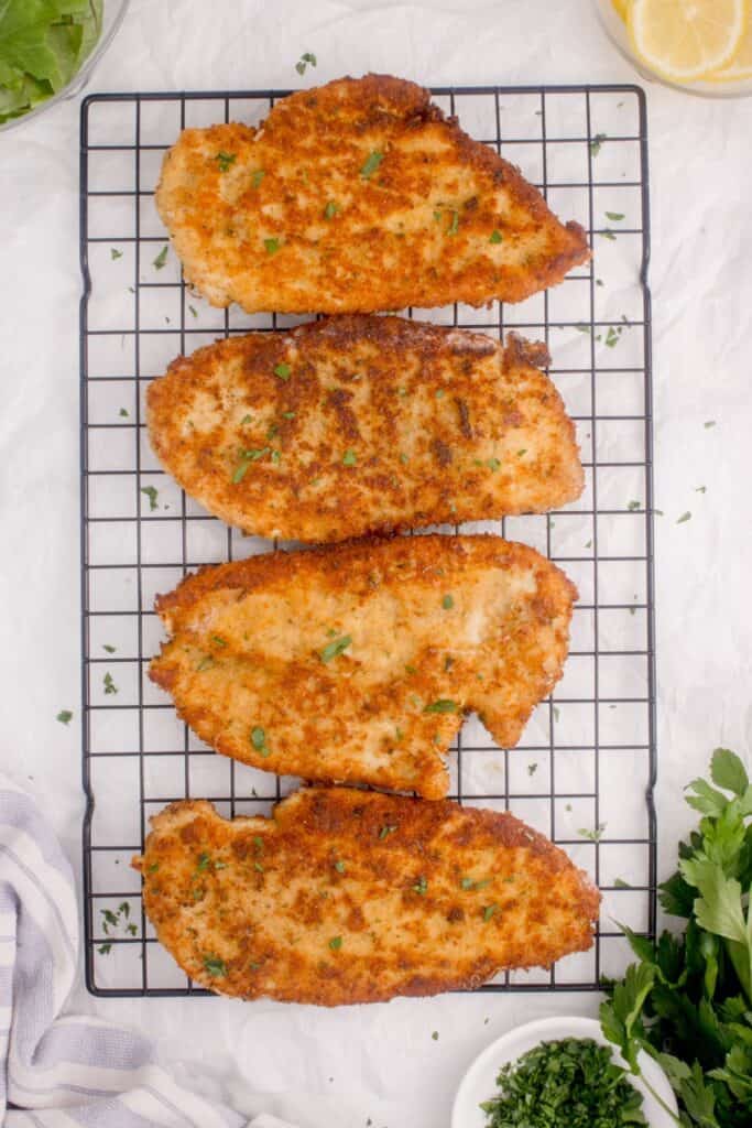 Baking rack with four pan fried chicken cutlets.