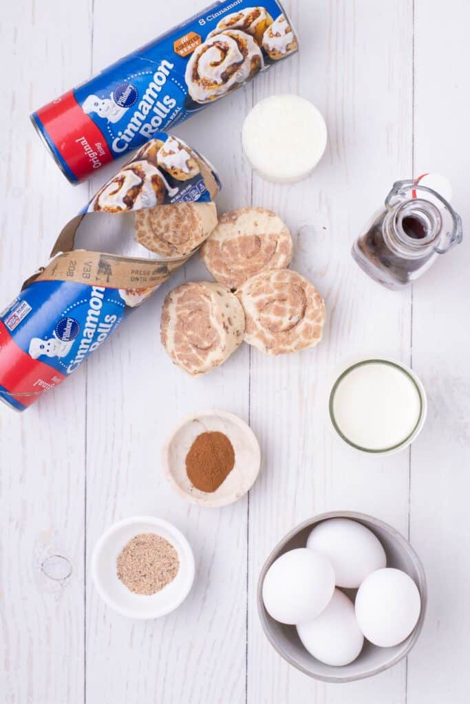 Ingredients for cinnamon roll casserole: Cinnamon Rolls with icing, Eggs, Heavy Cream, Cinnamon, Nutmeg, and Maple Syrup.