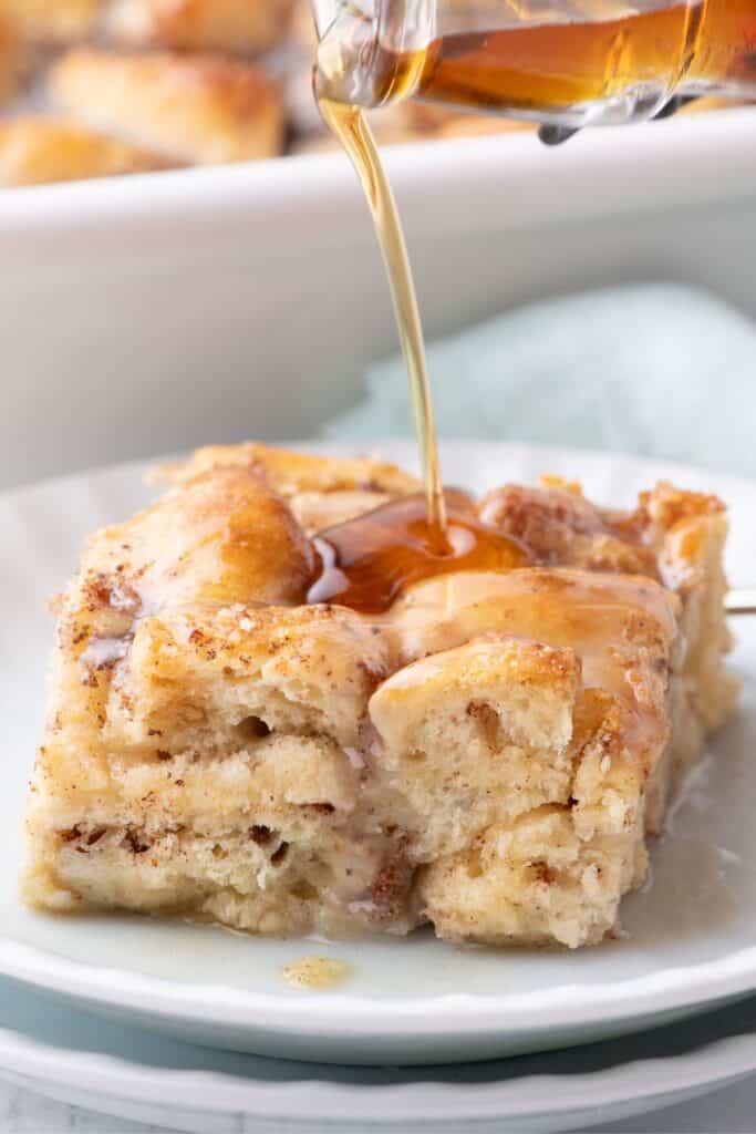 Slice of cinnamon roll casserole with a drizzle of maple syrup on top.