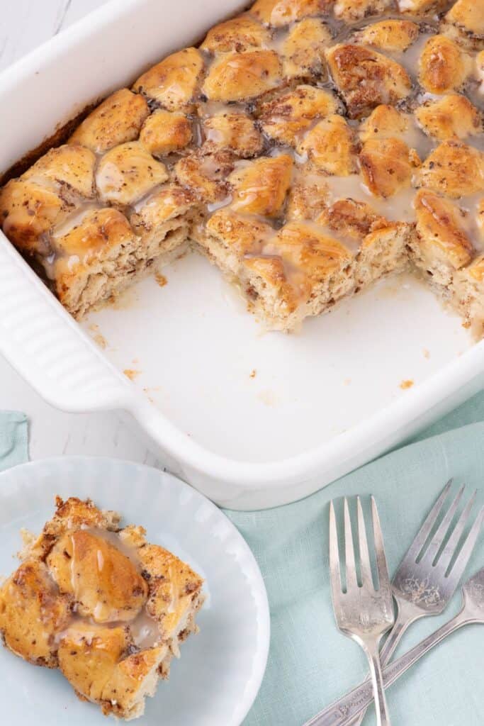 Cinnamon roll casserole in a white baking dish. A slice is served on a white dinner plate.