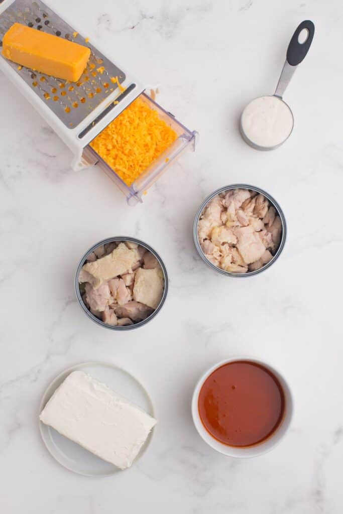 Ingredients for Buffalo chicken dip: Canned chicken, cream cheese, ranch dressing, Buffalo sauce, and cheddar cheese.