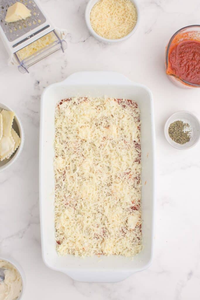 Lasagna in progress. Marinara sauce layered with shredded cheese.