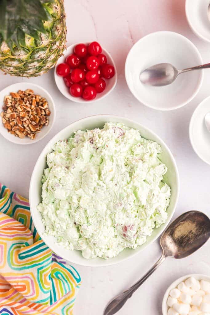 Ingredients for Watergate Salad: Crushed pineapple in juice, pistachio pudding mix, mini marshmallows, pecans, Cool whip, and maraschino cherries.