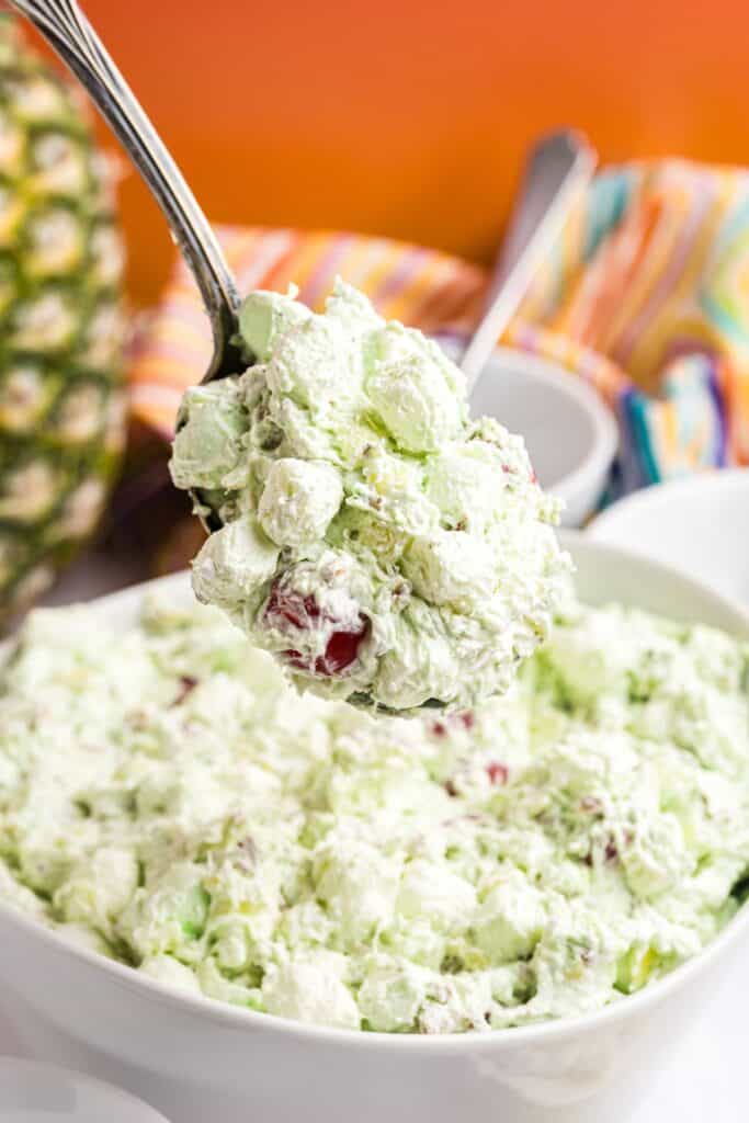 Spoonfull of jello salad being lifted above the large serving bowl.