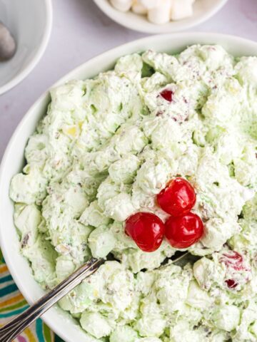 Large serving bowl of Watergate salad with a serving spoon in it.