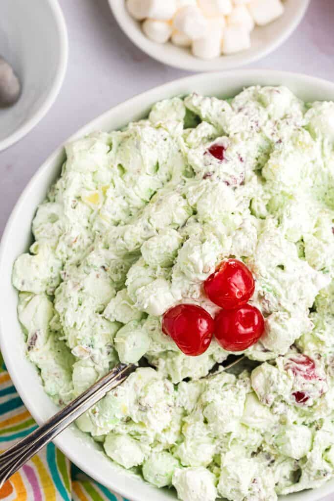 Large serving bowl of Watergate salad with a serving spoon in it.