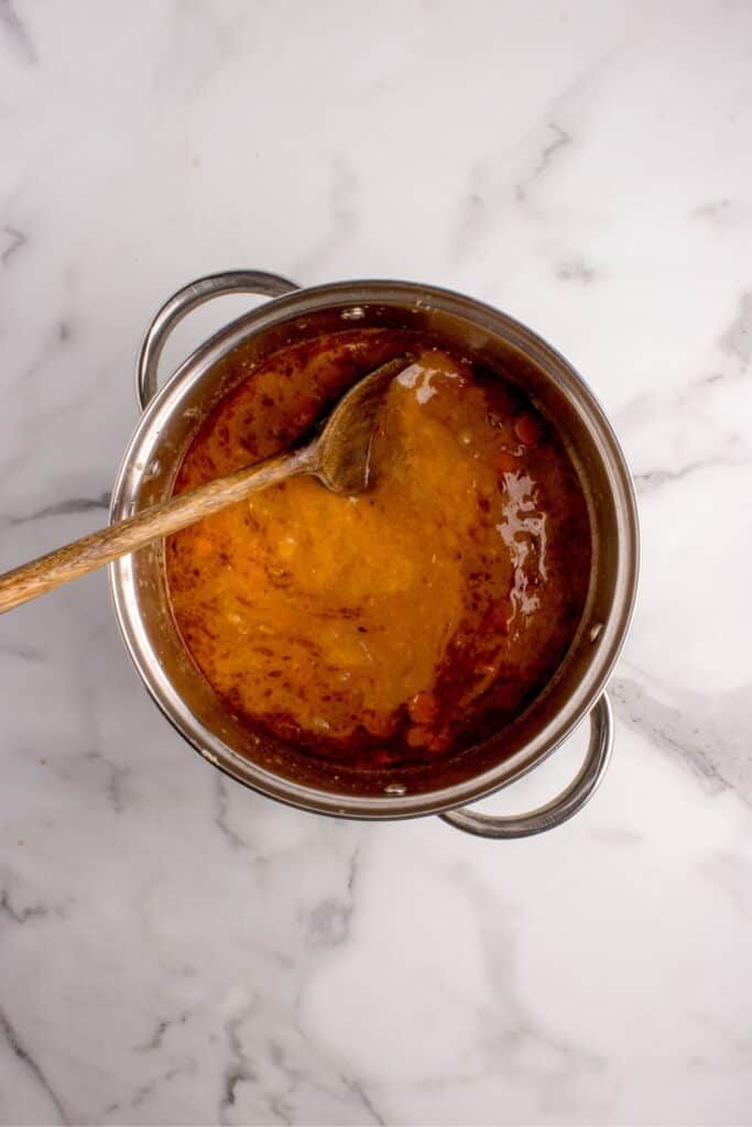 Pot of soup with a wooden spoon in it.