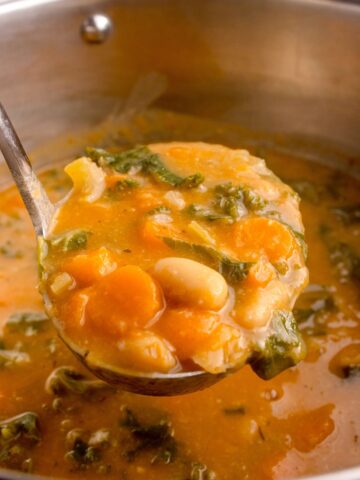 Big pot of bean soup with a ladle lifting up a serving.