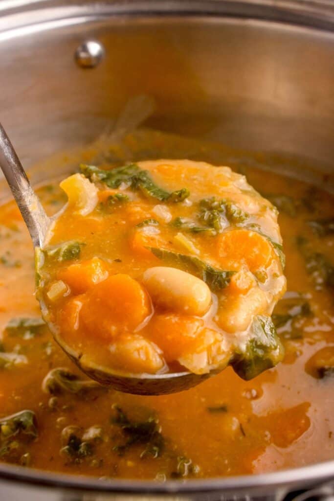 Big pot of bean soup with a ladle lifting up a serving.