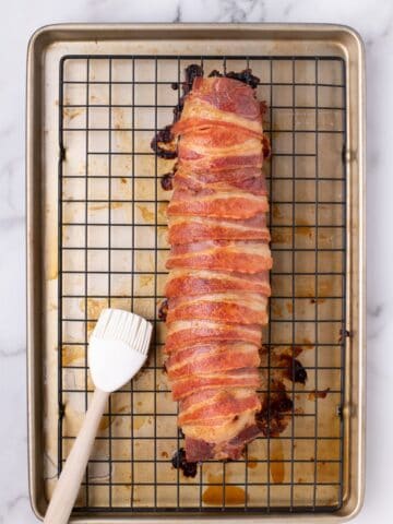 Tenderloin on a baking rack over a baking sheet. A silicone basting brush is next to it.