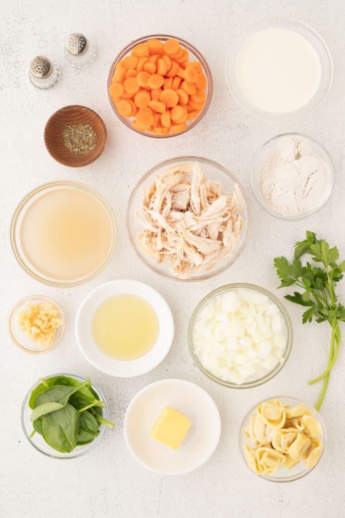 Ingredients for chicken tortellini soup: Butter, avocado oil, onion, carrots, garlic, salt and pepper, Italian seasoning, flour, chicken broth, rotisserie chicken, heavy whipping cream, cheese-filled tortellinis, parsley, and baby spinach.