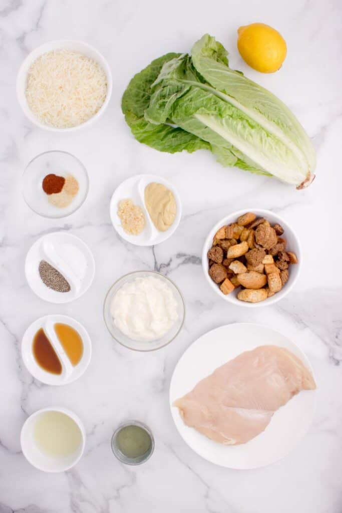 Ingredients for Chicken Caesar Salad: mayonnaise, parmesan cheese, garlic, mustard, fish sauce, Worcestershire sauce, fresh lemon juice, olive oil, salt, black pepper, chicken breast cutlet, onion powder, garlic powder, paprika, and olive oil.