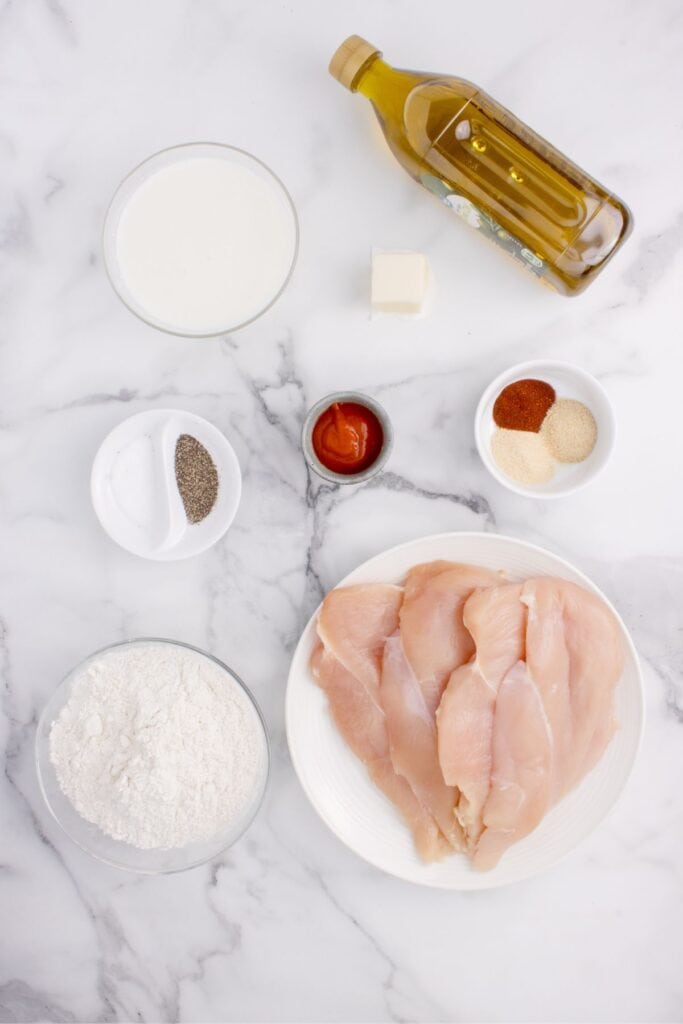 Ingredients for chicken fried chicken: chicken breasts, salt, pepper, milk, hot sauce, paprika, garlic powder, onion powder, flour, oil, and butter.