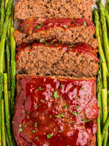 Completed and sliced meatloaf garnished with asparagus on both sides.