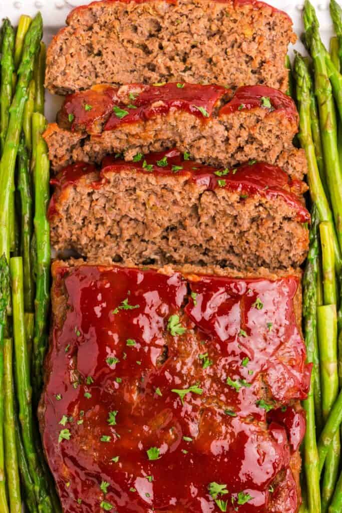 Completed and sliced meatloaf garnished with asparagus on both sides.