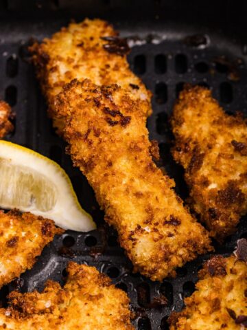 Close up of cooked fish sticks in the air fryer basket.