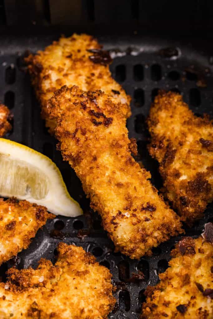 Close up of cooked fish sticks in the air fryer basket.