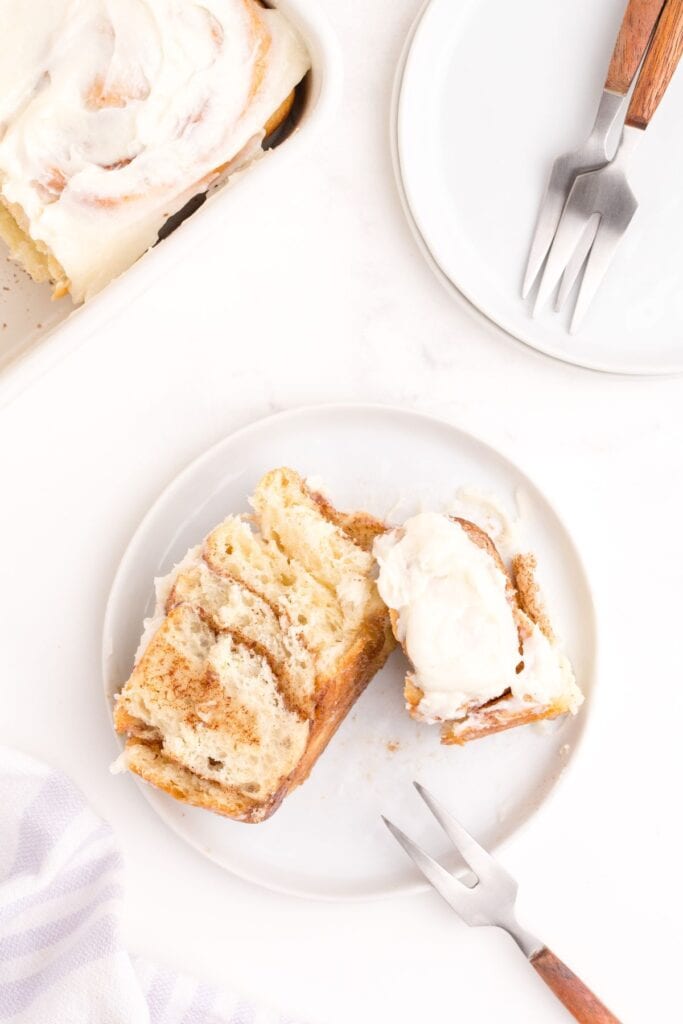 Baked cinnamon roll on a white salad plate.