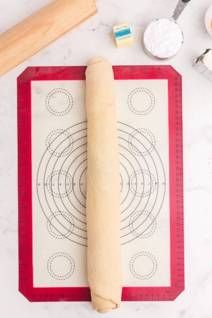 Cinnamon roll log on a silicone baking mat.