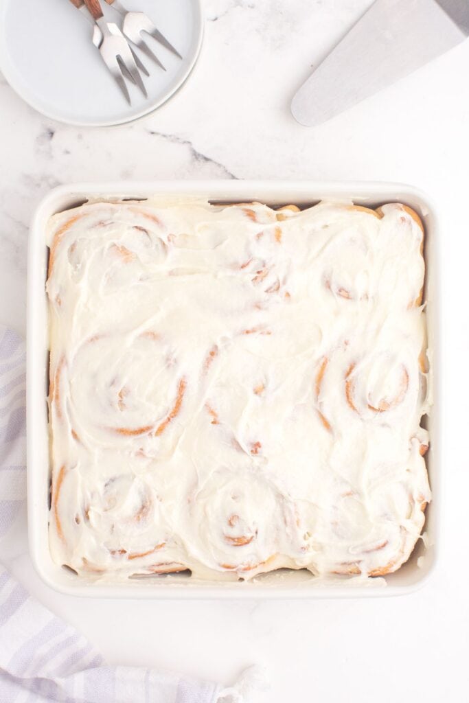 Overhead view of completed and iced cinnamon rolls in a baking pan.