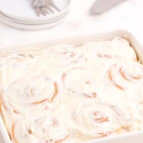 Completed and iced cinnamon rolls in a baking pan.