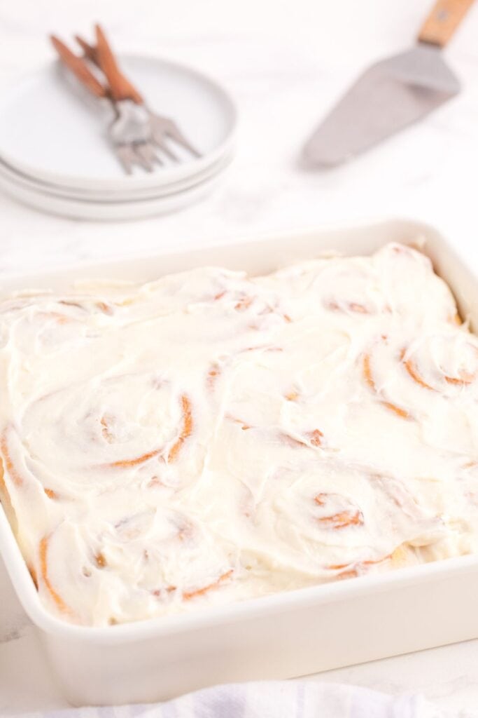 Completed and iced cinnamon rolls in a baking pan.