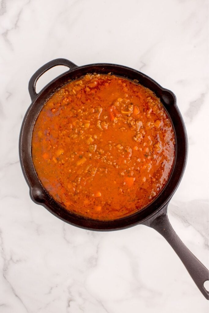 Pasta sauce cooking in a large skillet.