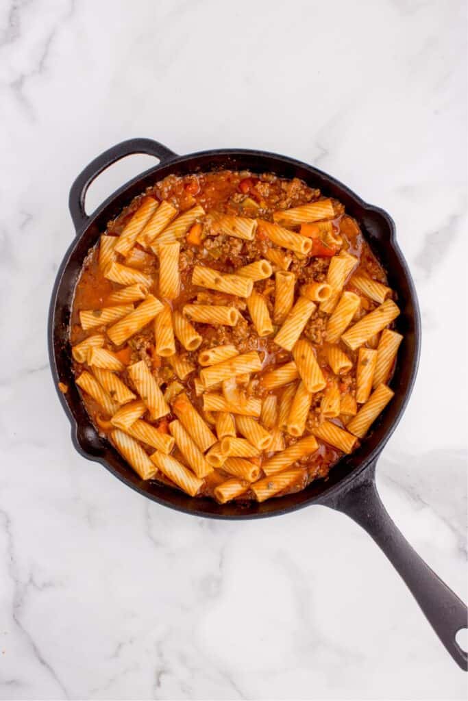 Overhead view of pasta bolognese in a large skillet.