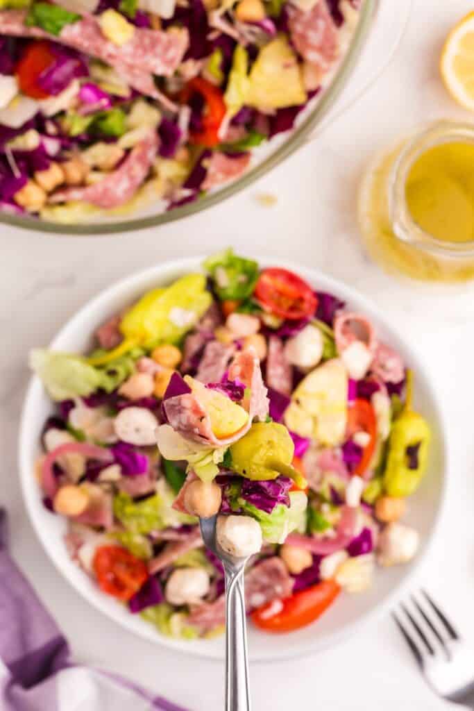 Chopped salad in a bowl. A fork is lifting up a bit to show the detail of the salad.