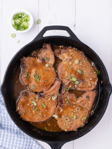 Completed honey garlic pork chops in a cast iron pan.