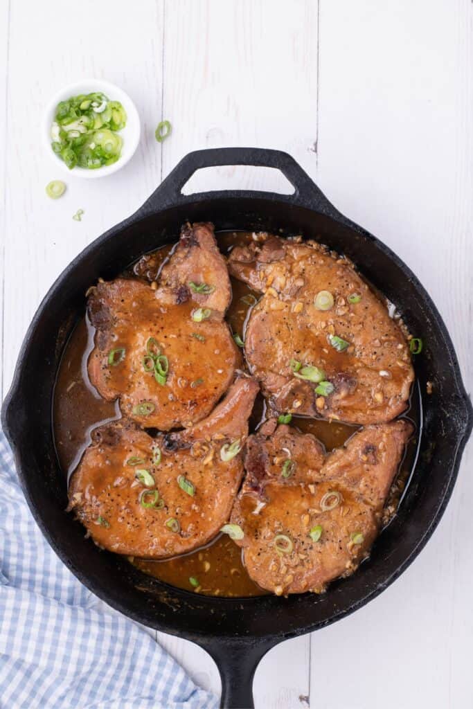 Completed honey garlic pork chops in a cast iron pan.