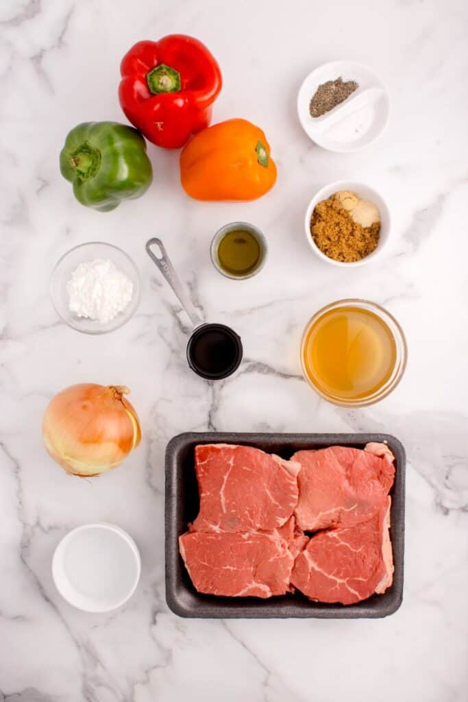 Ingredients for slow cooker pepper steak: sweet bell peppers, sirloin steak, yellow onion, beef stock, soy sauce, brown sugar, garlic powder, ground ginger, cornstarch, salt & pepper.