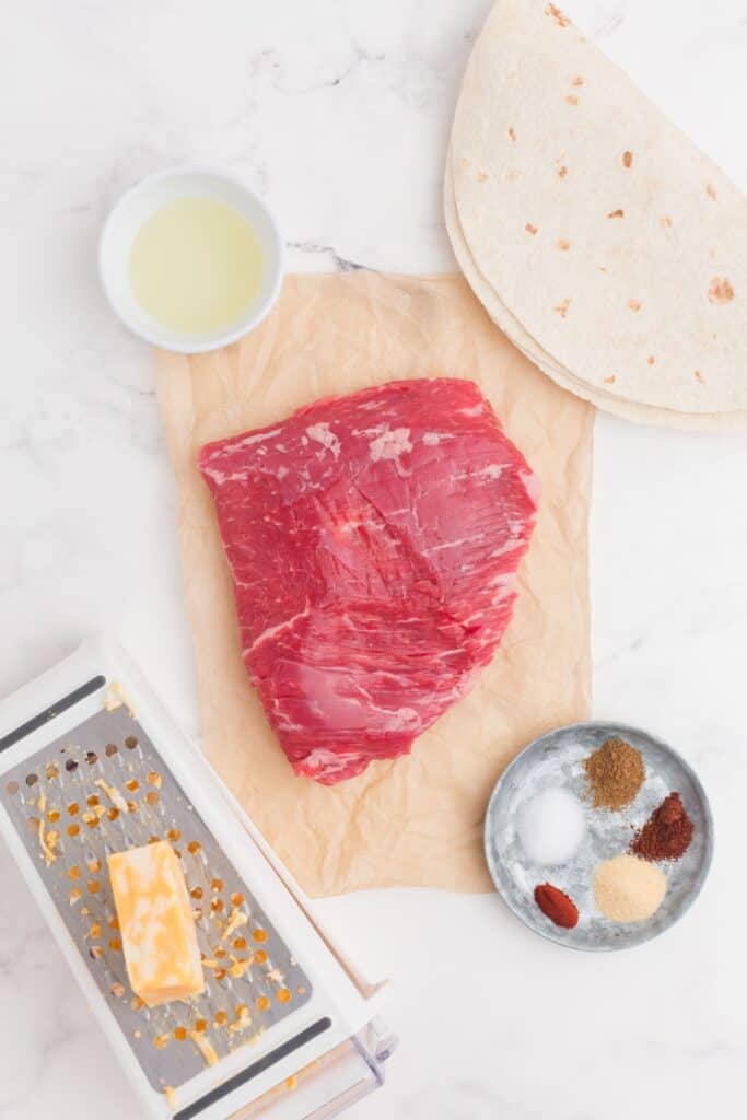 Ingredients for steak quesadillas: Flank steak, salt, cumin, chili powder, paprika, garlic powder, colby jack cheese, vegetable oil, and flour tortillas.