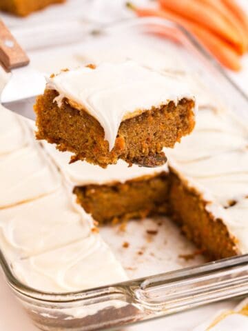 A serving of carrot cake lifted above the baking pan of carrot cake.