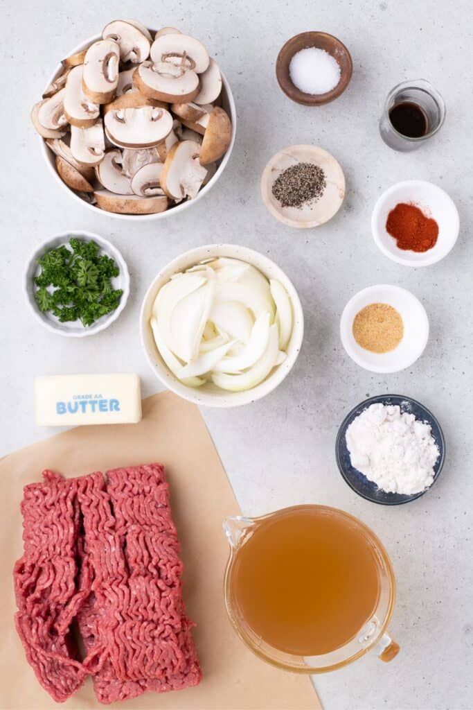 Ingredients for hamburger steak: ground beef, smoked paprika, garlic powder, salt and black pepper, onions, mushrooms, worcestershire sauce, all-purpose flour, beef broth, and fresh parsley.